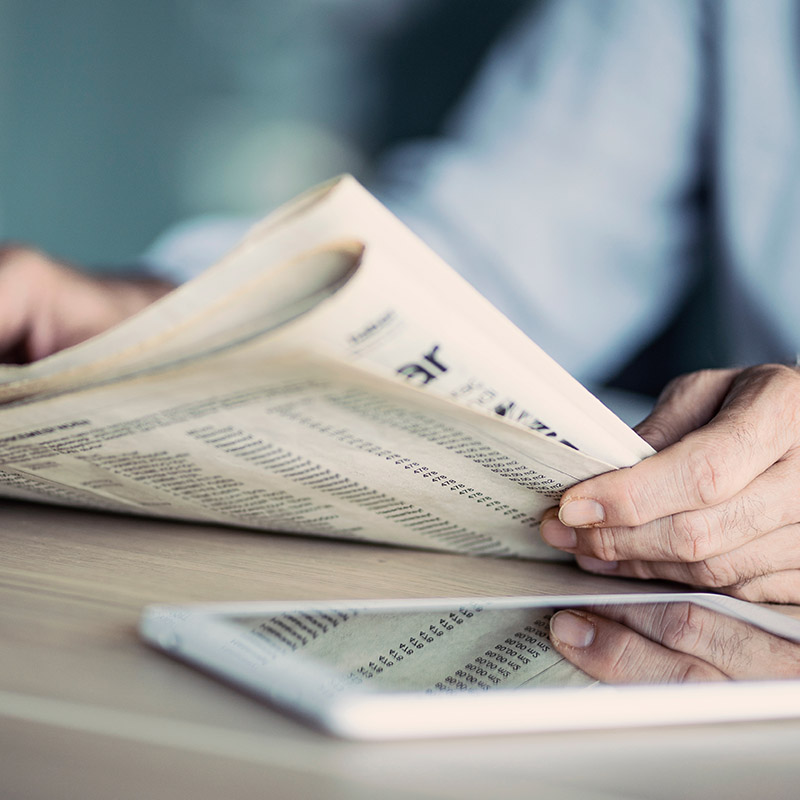 Mann beim Zeitungslesen mit Tablet